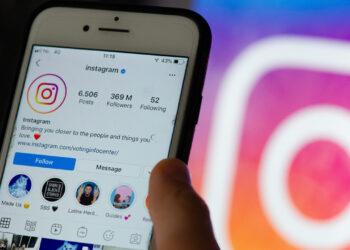 Arka planda Instagram logosu ve önde telefonda açık Instagram uygulaması