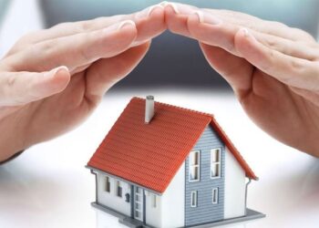 Elleriyle maket bir evin üstünü kapatan kişi