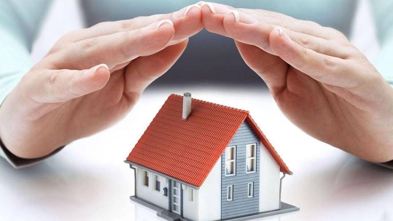 Elleriyle maket bir evin üstünü kapatan kişi